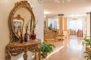 An ornate room with a large mirror, a marble console table, and a chandelier.