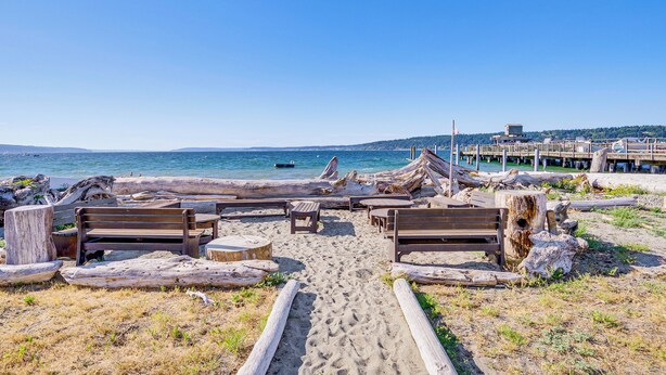 Una platja amb bancs de fusta i una passera de fusta que condueix a l'aigua.