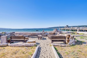 A beach with wooden benches and a wooden walkway leading to the water. - Sun-Soaked Sandy Point Haven w/ Beach Access! (Langley)