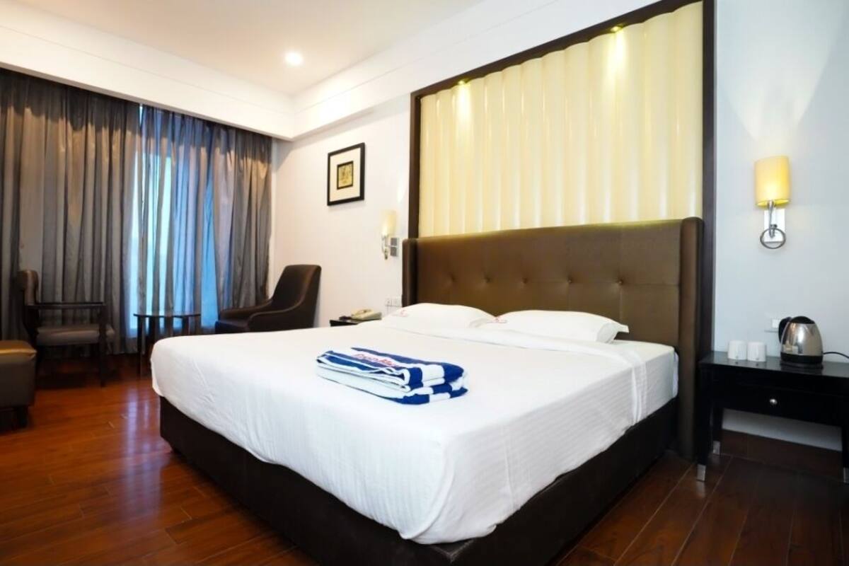 Una habitación de hotel con una cama grande, una silla, un escritorio y una mesita de noche.