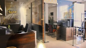 Et moderne kontormiljø med glasvægge, en reception og et spiseområde med stole og bord.