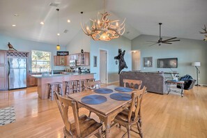Un'ampia zona giorno con un tavolo da pranzo in legno, un grande lampadario e una ventola a soffitto.