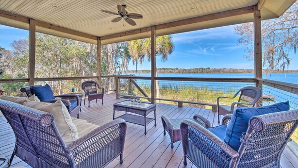 A covered deck with wicker furniture and a view of a lake. - Waterfront Home w/ Private Dock in Crystal River (Crystal River)
