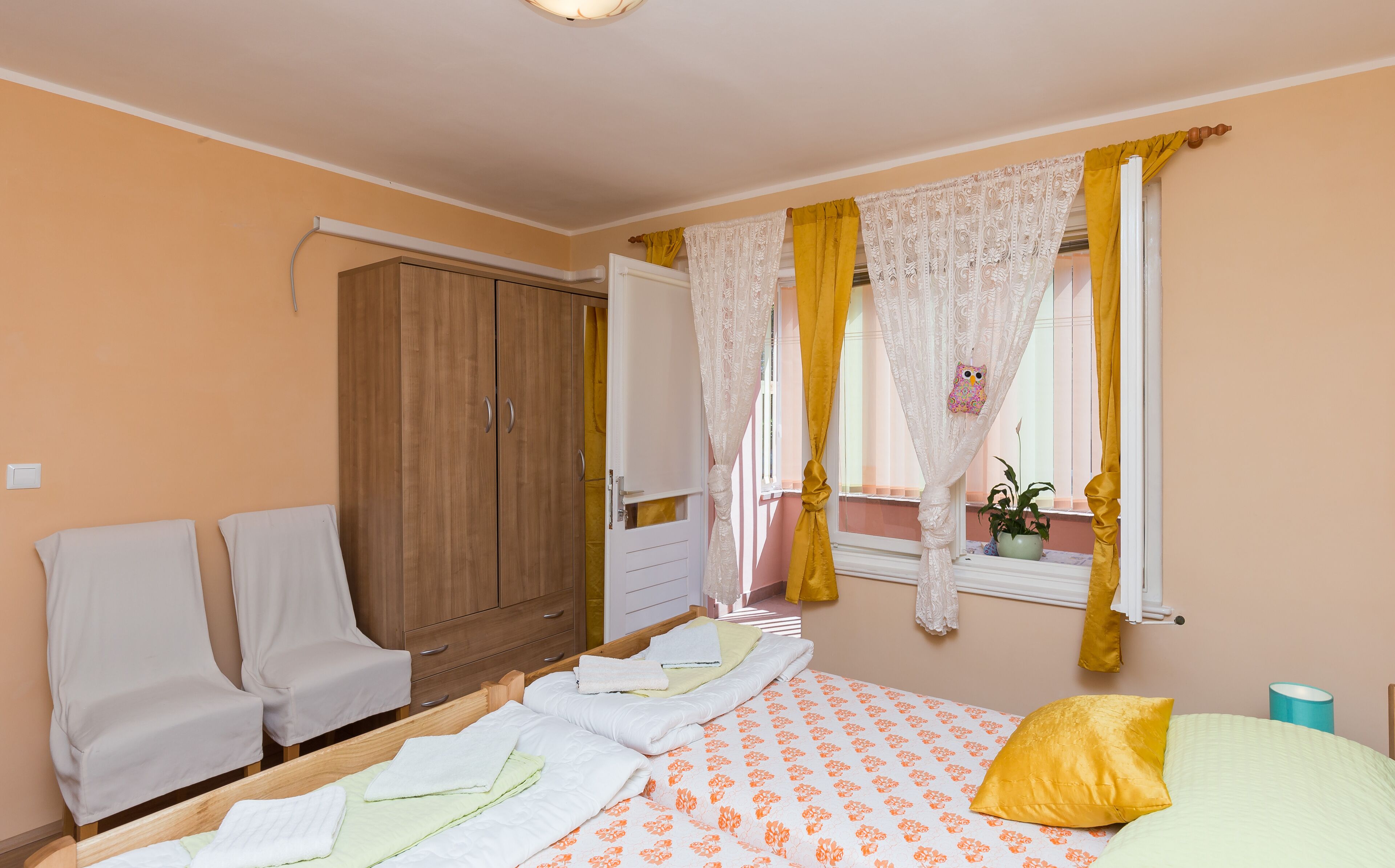 A bedroom with a bed, a wardrobe, a window with curtains, and a bedside table.