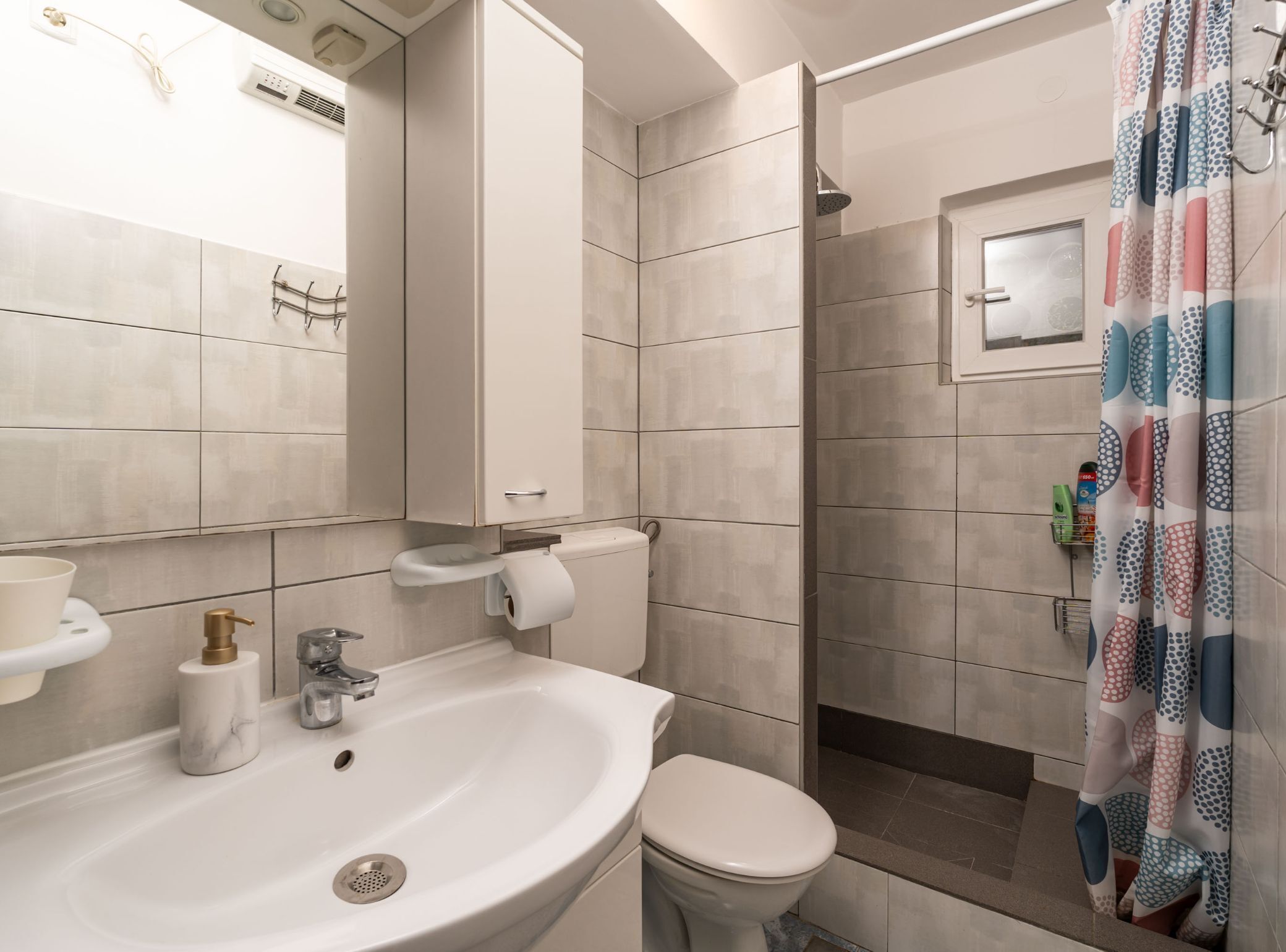 Un baño con lavamanos, inodoro y zona de ducha.