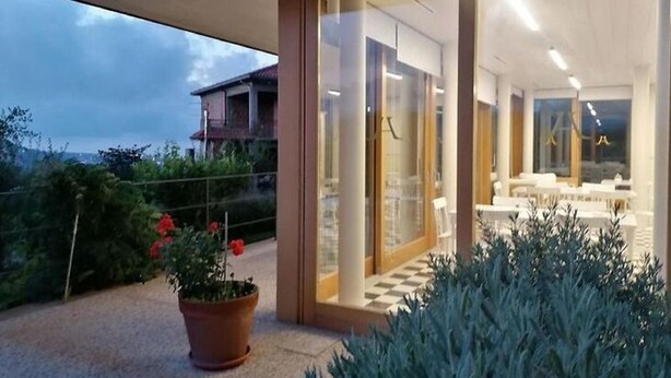 A modern hotel interior with a checkered floor, a glass door entrance, and a view of the surrounding landscape. - Belvilla by OYO Hotel Alimunera (Naso)