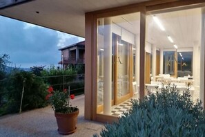 Een modern hotelinterieur met een geruit vloertje, een glazen deuropening en uitzicht op het omliggende landschap.