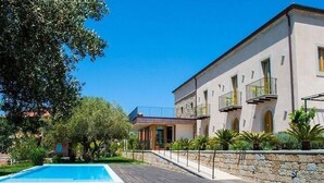 A two-story building with a swimming pool, stone walls, and a well-maintained garden. - Belvilla by OYO Hotel Alimunera (Naso)