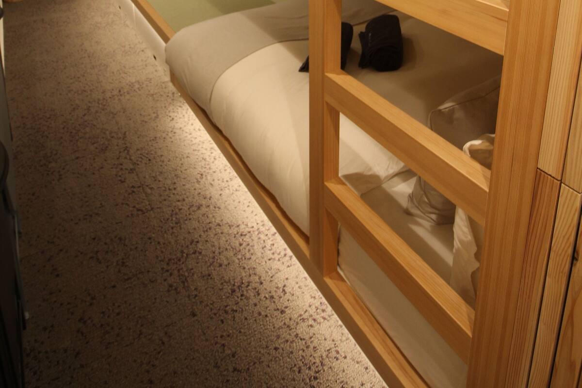 A bunk bed room with a desk and chair, a small table, and a window with curtains.