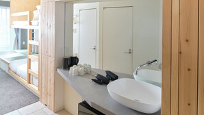A modern bathroom with a large mirror, a white sink, and a built-in bench with storage. - Sakura Cross Hotel Uenoiriya Annex (Tokyo)