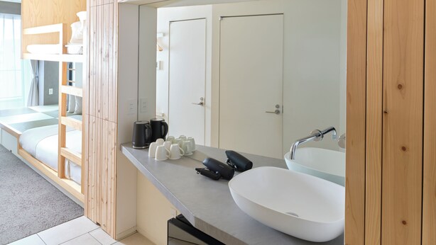 A modern bathroom with a large mirror, a white sink, and a built-in bench with storage.