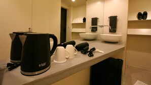A hotel bathroom with a sink, mirror, towel rack, and a coffee maker.