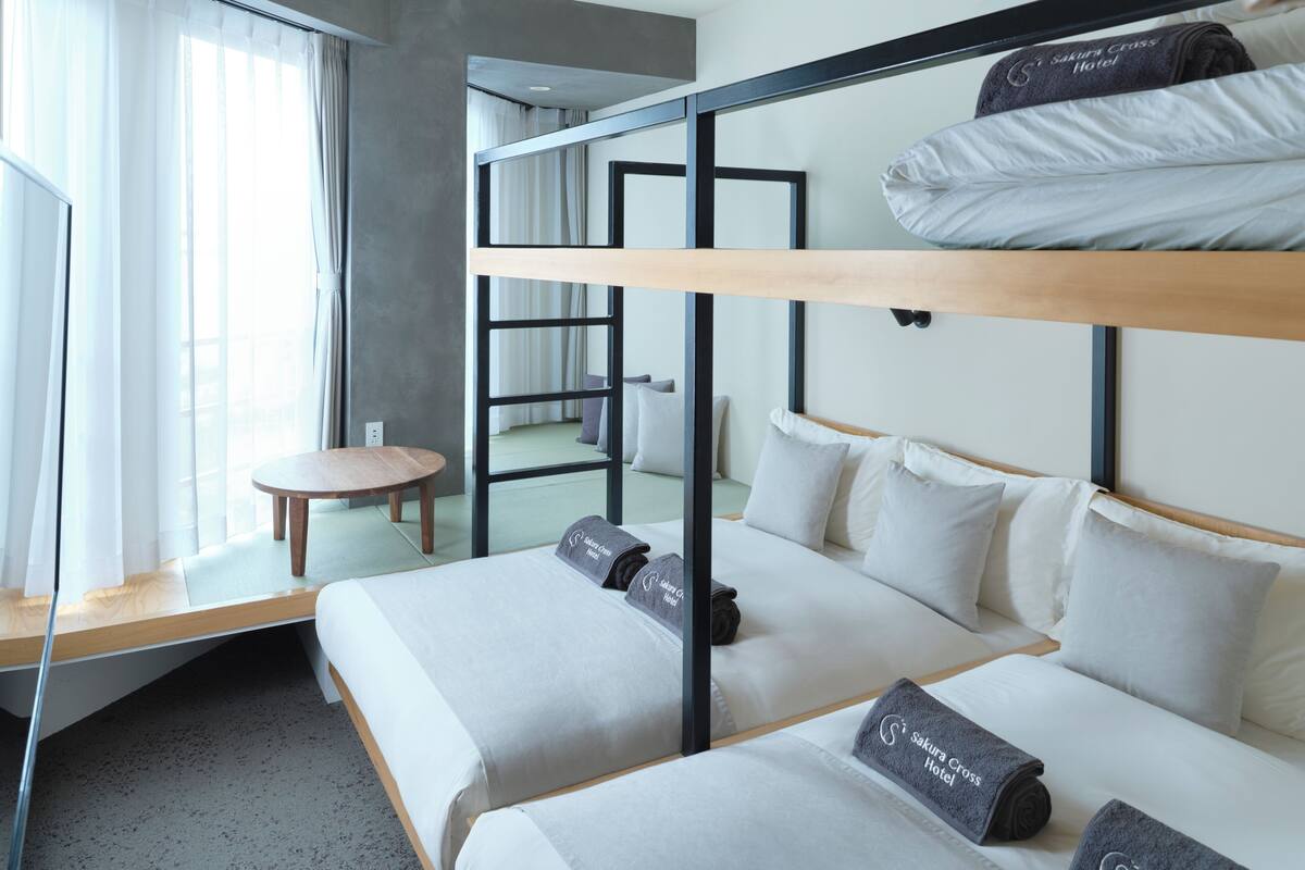 A hotel room with two beds, a small round table, and a large window with curtains.