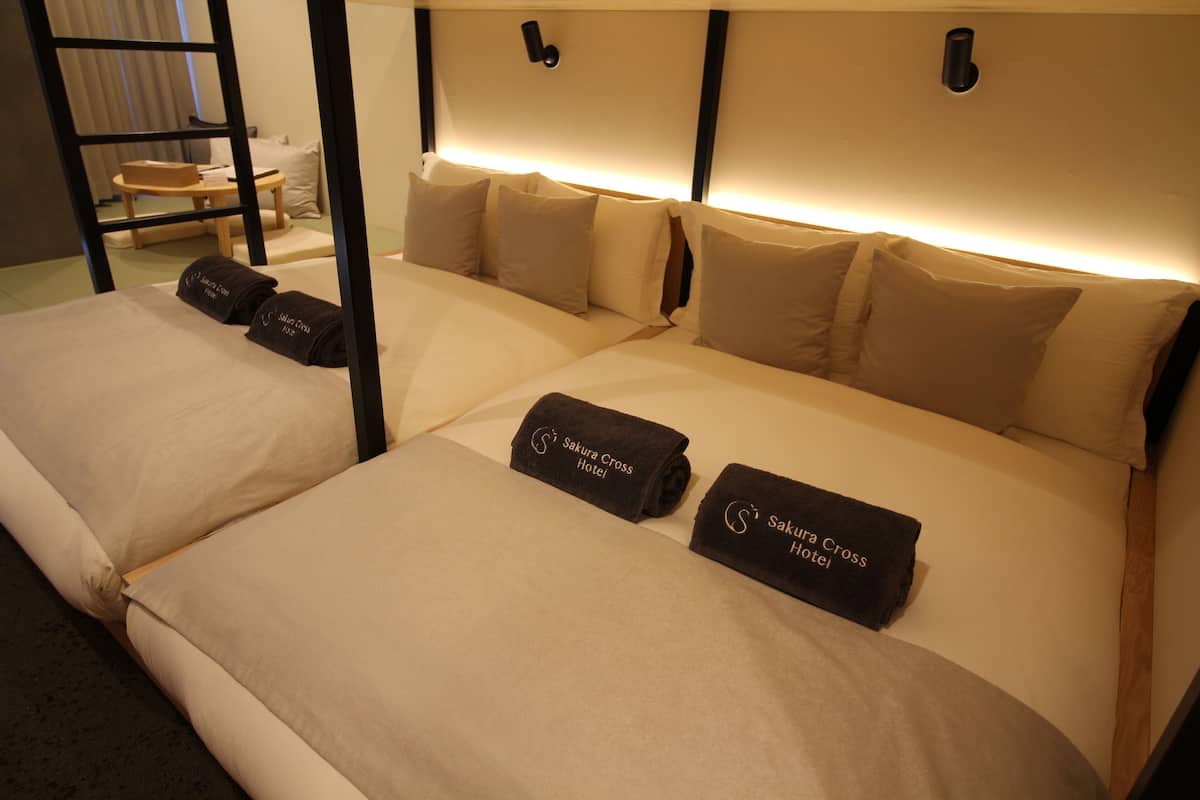 A hotel room with two beds, each with a headboard, pillows, and towels.