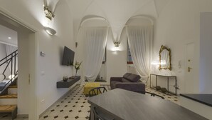 Ein modernes Wohnzimmer mit Essbereich, Treppe und großem Spiegel.
