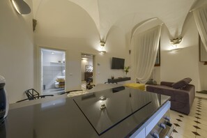 A modern living room with a large black glass table, a sofa, and a TV mounted on the wall. - Renovated apartment within walking distance of Palazzo Pitti and Pzza Santo Spirito (Firenze)