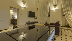 Eine moderne Küche mit einer zentralen Kochinsel, einem Essbereich mit einer Couch und einer Treppe, die zu einer oberen Etage führt.