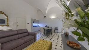 Ein modernes Wohnzimmer mit einer Couch, einem Hocker und einem Essbereich mit Stühlen und einem Tisch.
