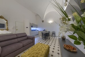 A modern living room with a sofa, ottoman, and a dining area with chairs and a table. - Renovated apartment within walking distance of Palazzo Pitti and Pzza Santo Spirito (Firenze)