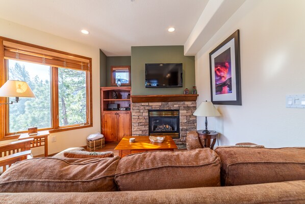 A cozy living room with a fireplace, wooden furniture, and a television mounted above it. - Luxury Ski-in/Ski-out at Eagle Run, Wifi, Garage & SPA (Mammoth Lakes)