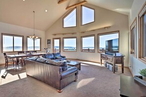 Amplia sala de estar con un sofá seccional grande, un comedor y amplias ventanas con vistas al exterior.