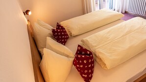 Habitación de hotel con dos camas, ropa de cama blanca y una ventana con cortinas.