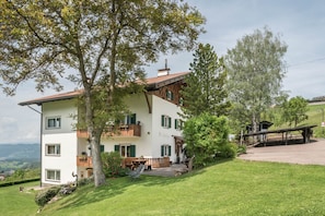 A multi-story building with balconies, a patio area, and a view of the countryside.