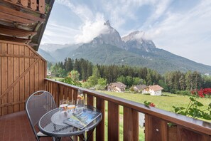 Un balcon avec une table, des chaises et une vue sur les montagnes.