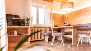 Una habitación acogedora de estilo cabaña con paredes de madera, una mesa de comedor con sillas, un televisor y una ventana con cortinas.
