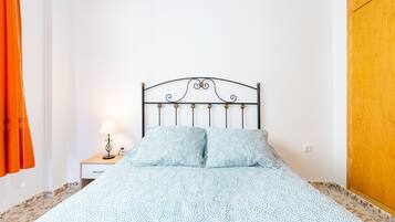 Ein Schlafzimmer mit einem Bett, einem Nachttisch, einer Lampe und einer Holztür.