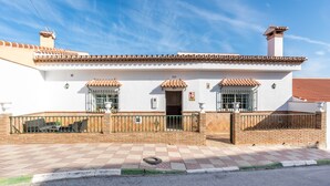 Un edifici blanc amb teulada de rajola, entrada tancada amb reixat i carrer d'accés pavimentat.