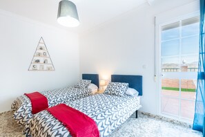 Ein Schlafzimmer mit Bett, Nachttisch, Wandbild und Blick durch eine Tür.