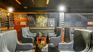 A modern interior with leather seating, a glass table, and a decorative tree mural. - Treebo Symphony Hotels And Resorts Angamally (Chalakudy)