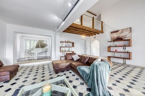 A spacious living area with a large sectional sofa, a coffee table, and a staircase leading to an upper level.
