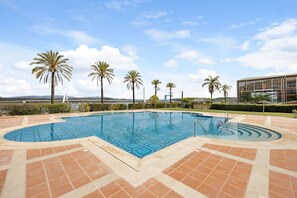 A swimming pool with a geometric tile pattern, surrounded by palm trees and a clear sky. - Boca do Rio - Apartamento T1 close to the Sea with Shared Pool & Wi-Fi (Lagoa)