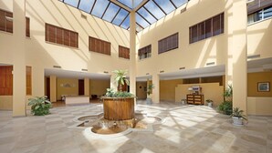 Un vaste atrium doté d’un élément aquatique central, de plusieurs niveaux et de plantes en pot.