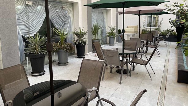 A patio area with outdoor seating, potted plants, and umbrellas. - Le Lido (Algiers)