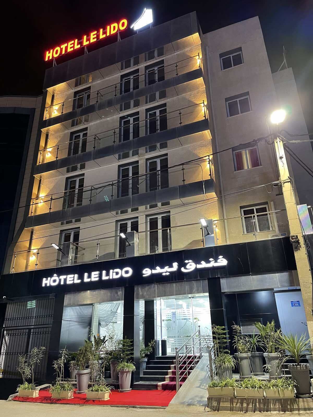A multi-story hotel with balconies and a red carpet entrance.