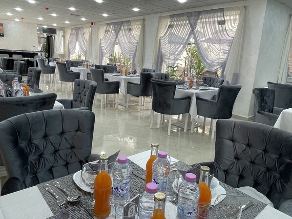 Un restaurante con mesas dispuestas para comer, sillas y diversas bebidas.