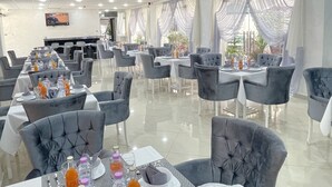 A spacious dining area with grey upholstered chairs and tables, each set with water bottles and glasses. - Le Lido (Algiers)