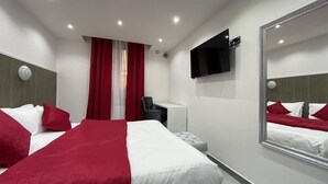A hotel room with two beds, a TV, a desk, and a mirror. - Le Lido (Algiers)