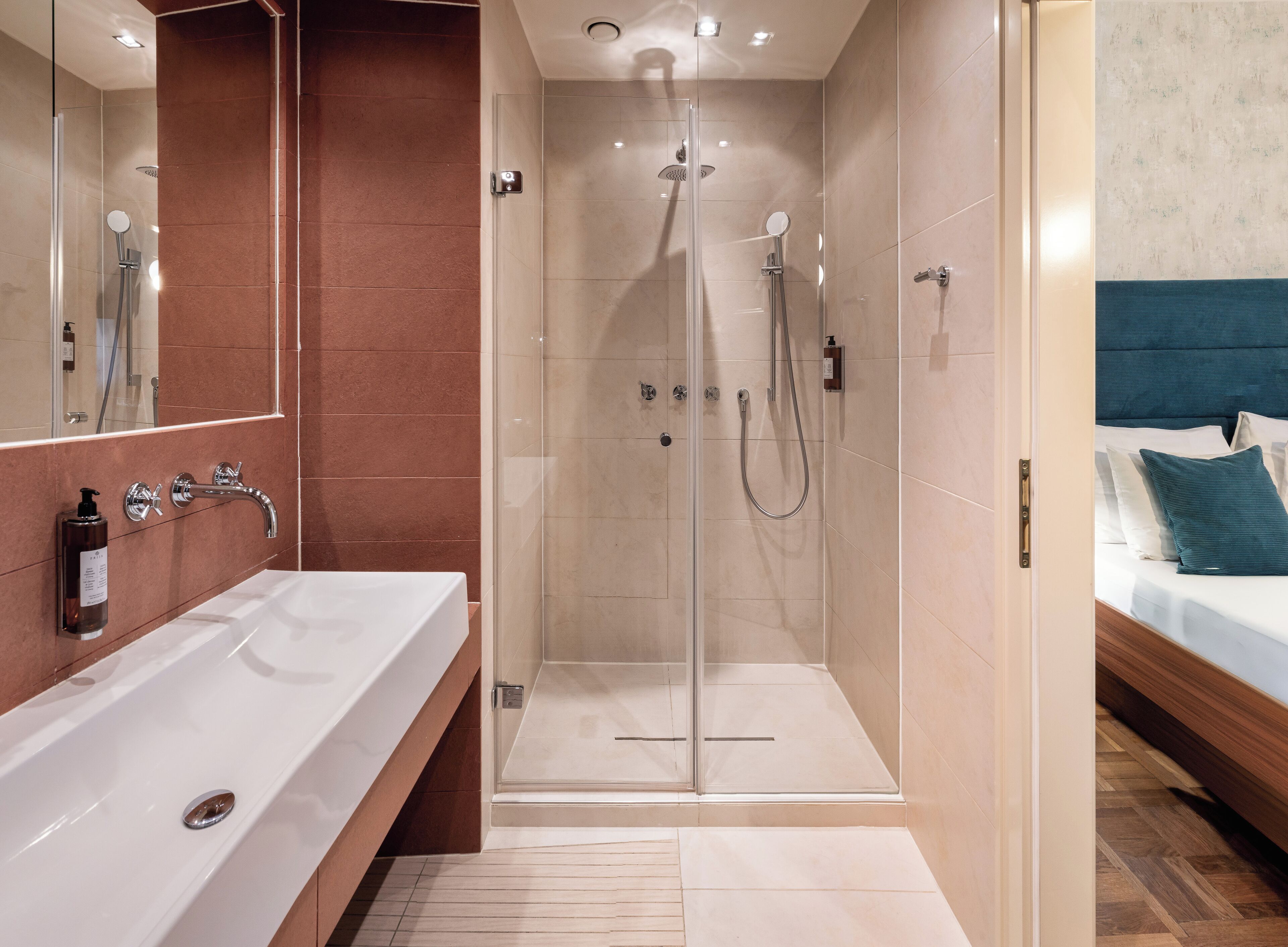 Un baño moderno con ducha de vidrio, lavamanos blanco y tocador de madera.