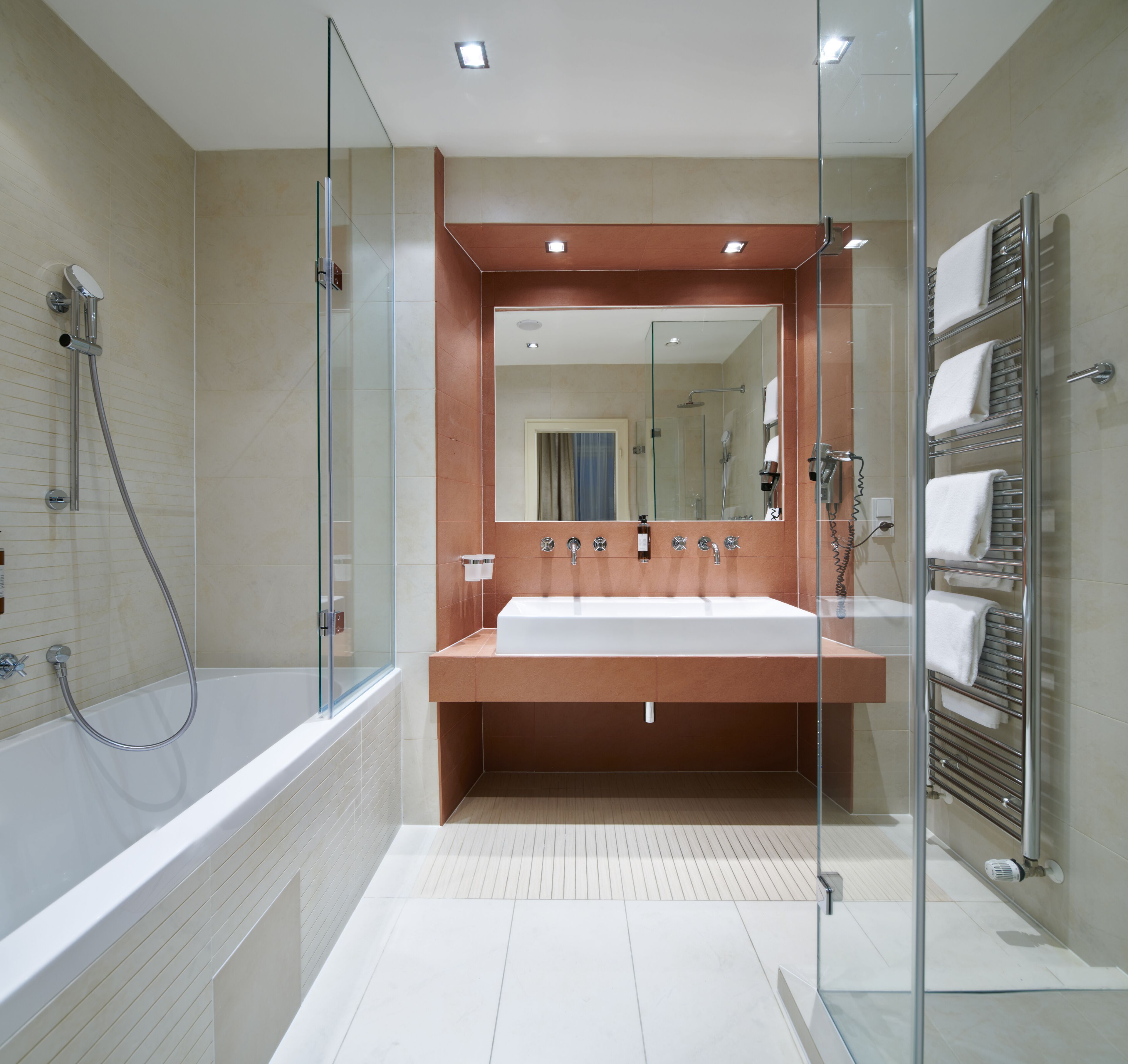 A modern bathroom with a glass-enclosed shower, a large sink, and a towel rack.