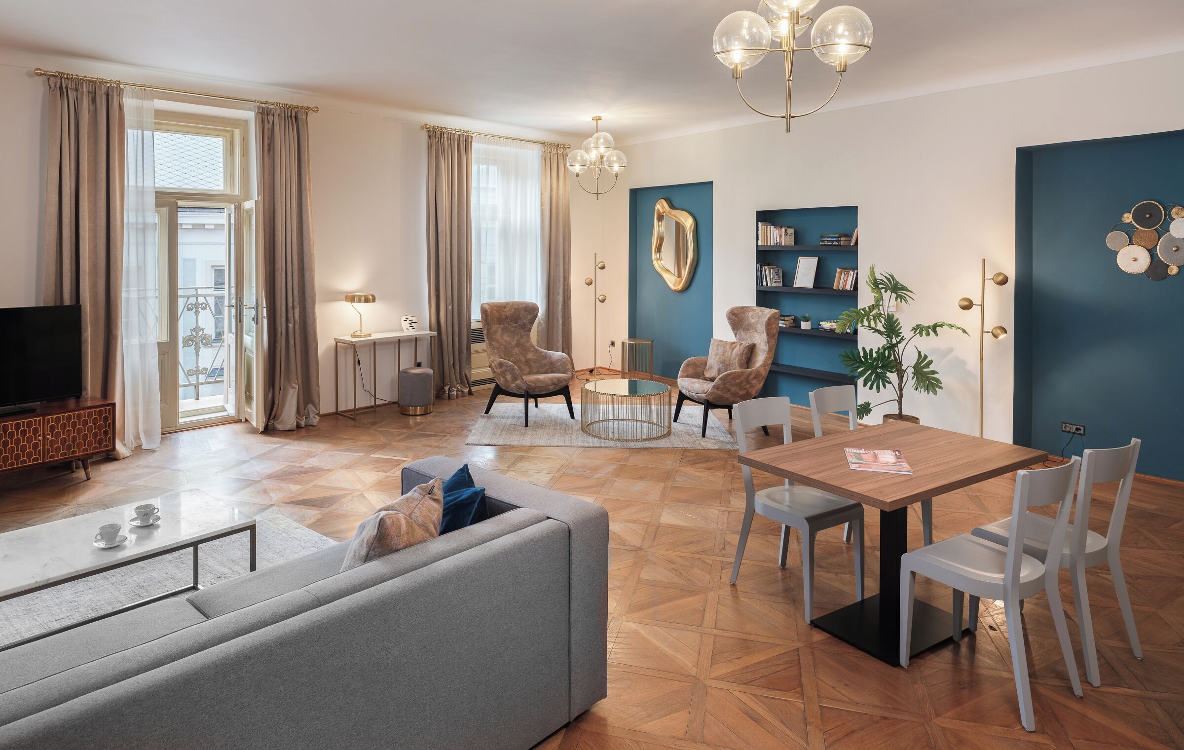 Uma sala de estar moderna com um sofá, poltronas, uma mesa de jantar com cadeiras, uma televisão e uma estante de livros.