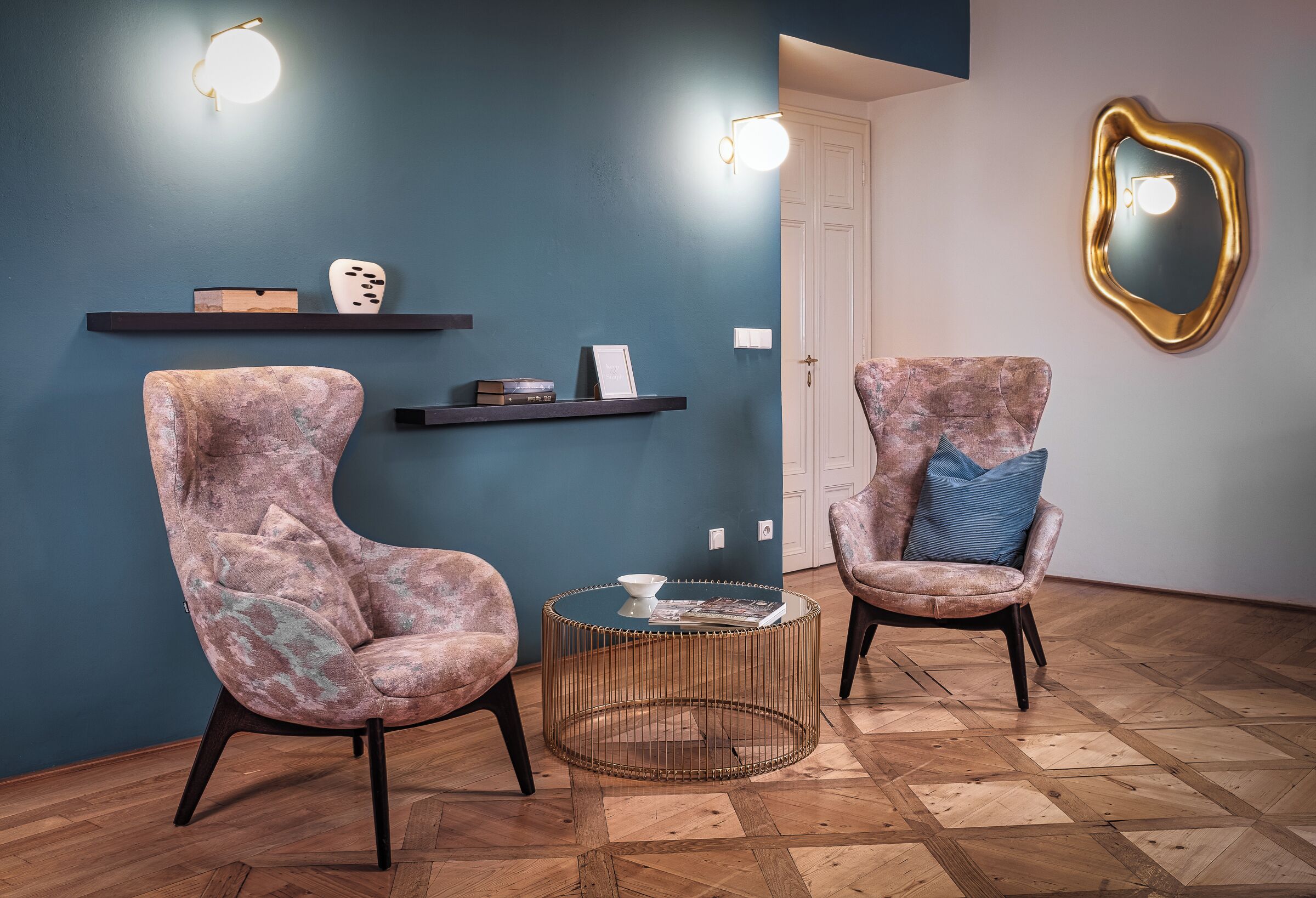 Ein Zimmer mit zwei Sesseln, einem runden Couchtisch und Wandregalen.