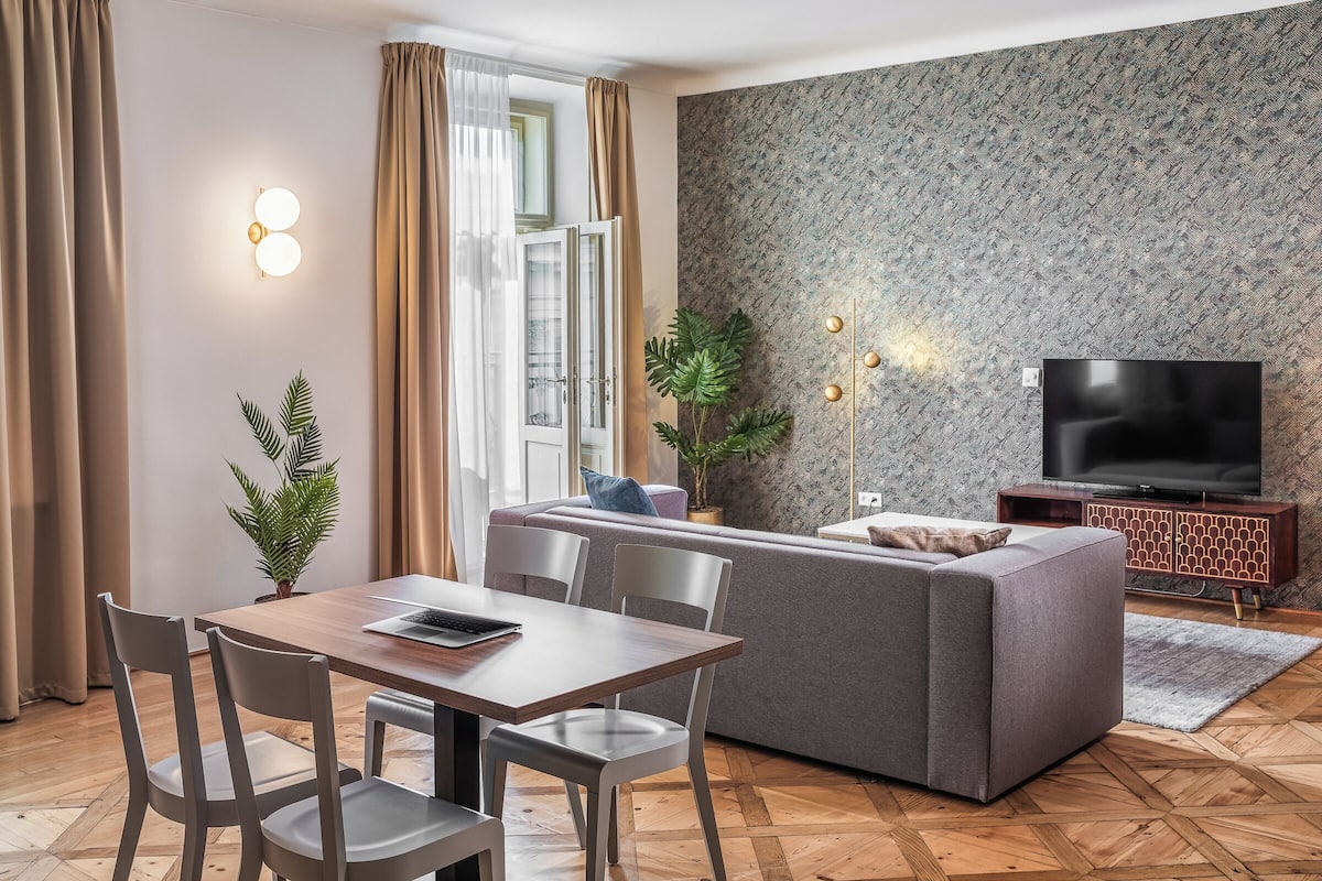 A modern living room with a sofa, dining table, chairs, and a TV.