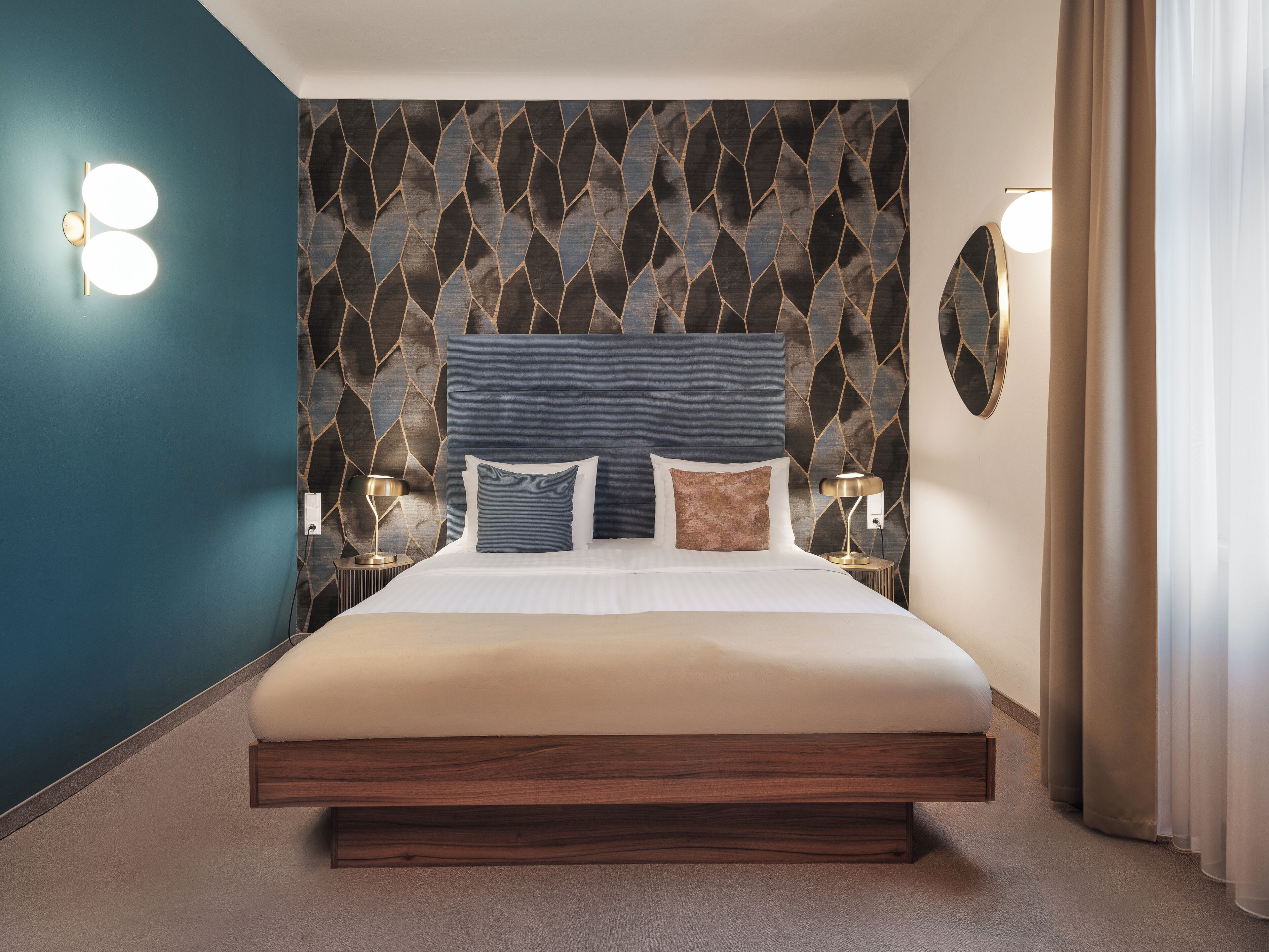 Ein modernes Hotelzimmer mit einem großen Bett, zwei Nachttischen und einem dekorativen Wandmuster.