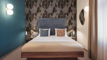 A modern hotel room with a large bed, two bedside tables, and a decorative wall pattern.