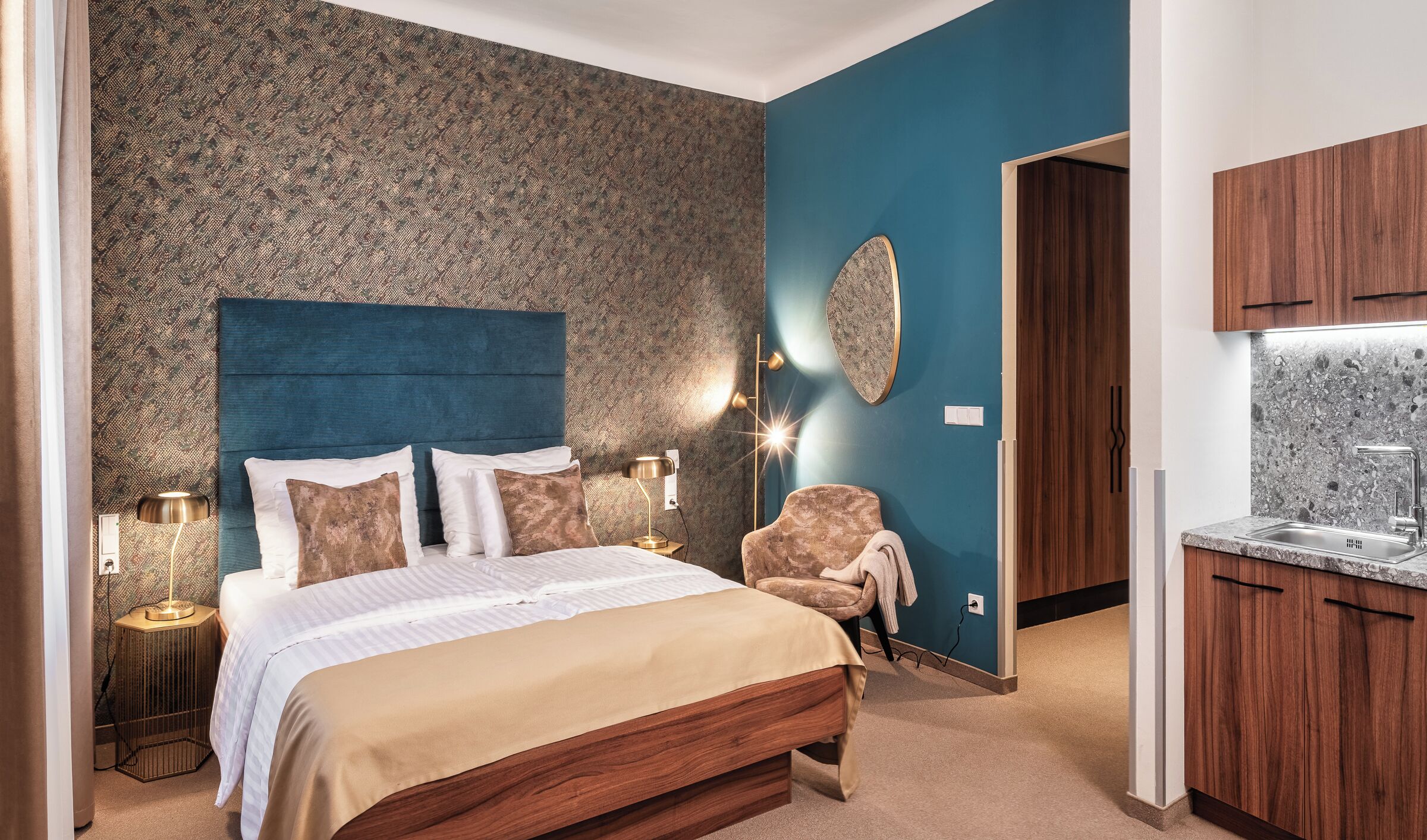 Une chambre à coucher avec un grand lit, une chaise, une table de chevet, une lampe et un luminaire fixé au mur.