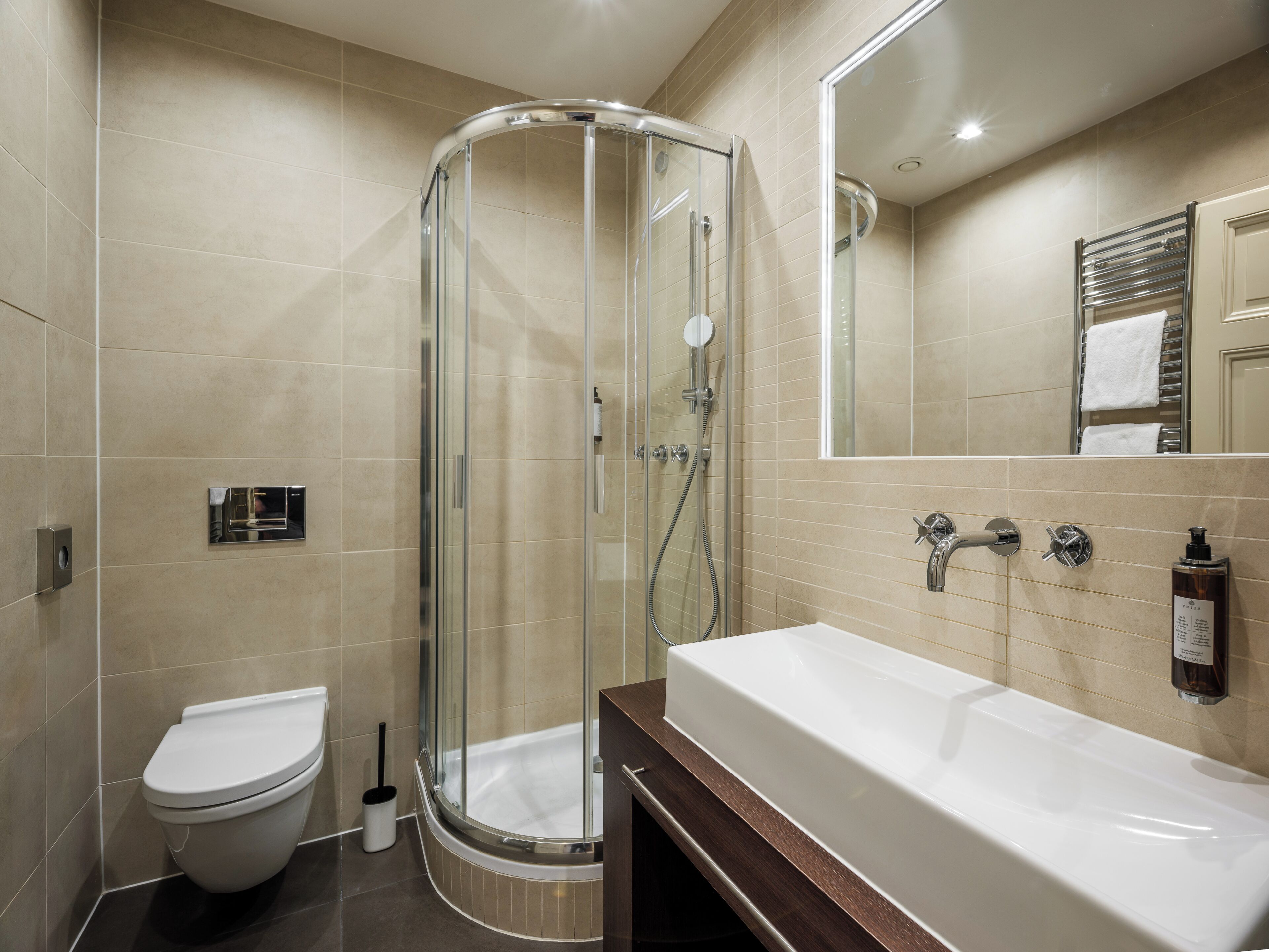 A modern bathroom with a glass-enclosed shower, a white toilet, and a large bathtub.